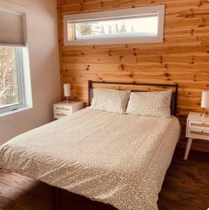a bedroom with a bed with two night stands and a window at NOvO Chalet in Saint-David-de-Falardeau