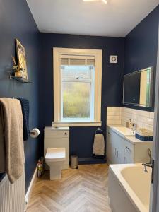 a blue bathroom with a toilet and a sink at Flat in Lundin Links in Lundin Links