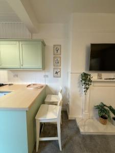 a kitchen with green cabinets and a table and a white chair at Flat in Lundin Links in Lundin Links