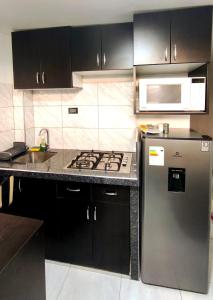 a kitchen with black cabinets and a stainless steel refrigerator at mini departamento Andahuaylas in Andahuaylas