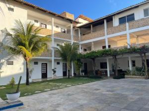 a large building with palm trees in the courtyard at Hospedaria Cumbuco - Kitnets Completas in Caucaia