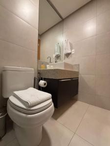 a bathroom with a white toilet and a sink at Apart St Bueno Ar, Cozinha, Garagem Próx Órion in Goiânia