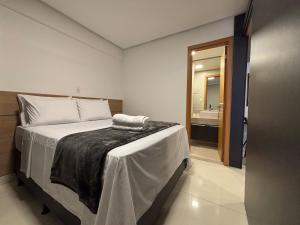 a bedroom with a bed and a bathroom at Apart St Bueno Ar, Cozinha, Garagem Próx Órion in Goiânia