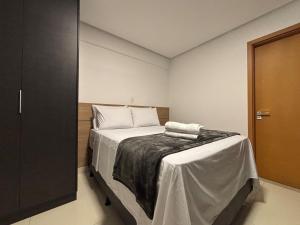 a bedroom with a bed with a blanket on it at Apart St Bueno Ar, Cozinha, Garagem Próx Órion in Goiânia