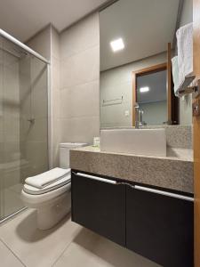 a bathroom with a toilet and a sink and a mirror at Apart St Bueno Ar, Cozinha, Garagem Próx Órion in Goiânia