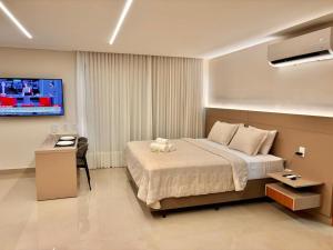 a hotel room with a bed and a television at Apart St Bueno SuperKing Ar, Cozinha, Vaga in Goiânia