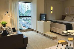 a bedroom with a bed and a tv and a couch at St Oeste Superking Ar, Cozinha, Office, Vaga in Goiânia