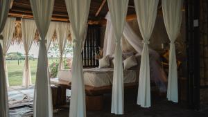 a bedroom with white curtains and a bed with a window at WISIRARE ECOLODGE - Luxury experience in Yopal