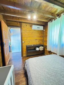a bedroom with a bed in a room with wooden walls at Cabanas Nascer do Sol in Santo Amaro da Imperatriz