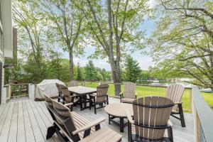 a deck with tables and chairs and trees at Starry Night by Railey Vacations in Swanton