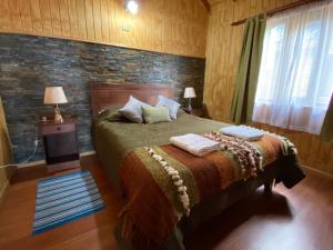 a bedroom with a bed and a brick wall at Cabañas Antonia in Futaleufú