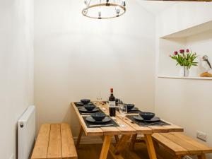a dining room with a wooden table with wine bottles at Wheelwright Cottage in Clunbury