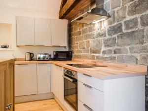 a kitchen with white cabinets and a stone wall at Wheelwright Cottage in Clunbury +16 photos