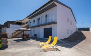 two yellow chairs and an umbrella in front of a building at Vila da Pesca House in Rabo de Peixe
