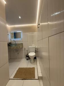 a white bathroom with a toilet and a mirror at Downtown Rooftop 375 in Imbetiba +35 photos