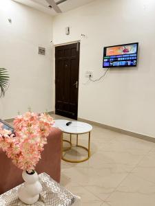 a room with a tv and a vase of flowers on a wall at Heartistry in Jabalpur