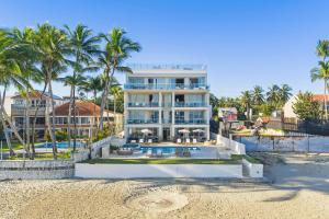 a building on the beach with a swimming pool and palm trees at Watermark Luxury Oceanfront Residences in Cabarete