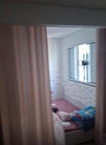 a dog laying on a bed in a room with a window at Aconchego in Cascavel +4 photos