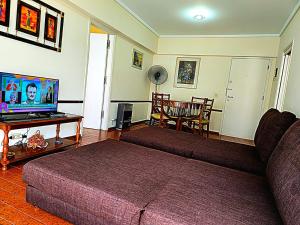 a living room with a couch and a table with a tv at La Perla Mar y Sol in Mar del Plata