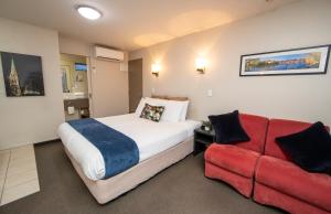 a bedroom with a bed and a red couch at Cranford Oak Motel in Christchurch
