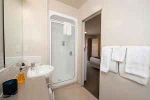 a bathroom with a sink and a shower with towels at Cranford Oak Motel in Christchurch +27 photos