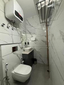 a white bathroom with a toilet and a sink at Conifer heights in Shimla