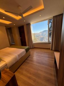 a bedroom with a bed and a large window at Conifer heights in Shimla