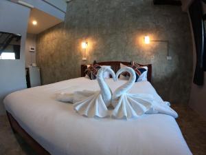 two white swans making a heart shape on a bed at โรงแรมบีคูลบูทีค in Ban Hua Phrong +16 photos