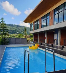 a yellow rubber duck in a swimming pool in front of a building at โรงแรมบีคูลบูทีค in Ban Hua Phrong