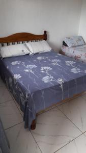 a bed with a blue blanket with white flowers on it at Hospedaje Tío Tom in Bernardo de Irigoyen