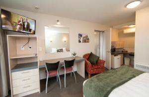 a bedroom with a bed and a desk and chairs at Cranford Oak Motel in Christchurch