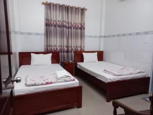 two beds sitting in a room withskirts at Nhà nghỉ KIM VÀNG in Phú Quốc