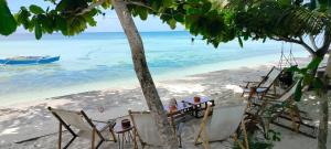 a table and chairs on a beach with a boat at Blue House Backpackers Siquijor in San Juan