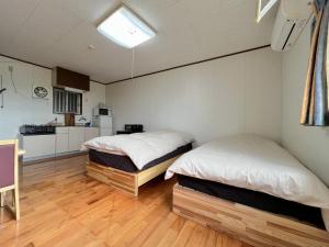 two beds in a room with a kitchen at ウィークリー宿家里 in Akaren