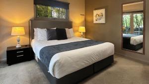 a bedroom with a large bed and a mirror at The Studio Suite at Villa 7 in Hepburn Springs