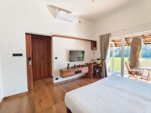 a bedroom with a bed and a television and a table at Vaigayi Ayurveda and Yoga Resort in Kodanad