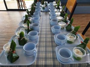a long table with blue cups and green plants on it at โรงแรมบีคูลบูทีค in Ban Hua Phrong