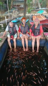 three people sitting on a boat with fish in the water at Sawani Home in Ambalangoda