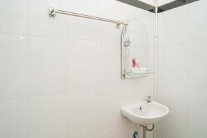 a white bathroom with a sink and a mirror at RedDoorz Syariah At Mitra Guest House in Malang +77 photos