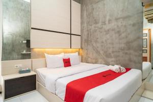 a bedroom with two beds and a red blanket at RedDoorz Syariah At Mitra Guest House in Malang