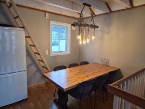 a dining room with a table and chairs and a refrigerator at Tjeldsund Tide nr. 6 in Steinsland