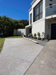 a driveway leading to a white building with plants at Quiet restful unit with seaviews in Auckland
