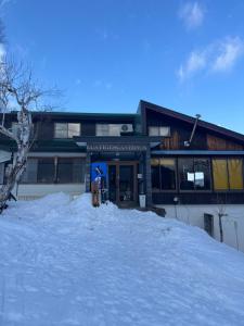 a building with a pile of snow in front of it at ゲストハウスルスティゲス in Kijimadaira