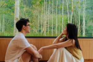 a man and a woman sitting in front of a window at Blue Diamond Retreat in Vực Trô