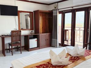 a bedroom with a large bed with a desk and windows at Vang Vieng Sisavang Hotel in Vang Vieng