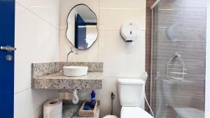 a bathroom with a sink and a mirror and a toilet at Suítes Santorini | The Férias - Aconchego no Centro de Arraial do Cabo com Cozinha Compartilhada e AR in Arraial do Cabo