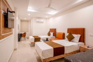 a hotel room with two beds and a television at Hotel Helixo Classic Kompally in Hyderabad