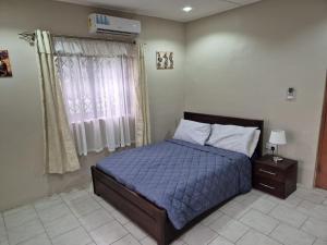 a bedroom with a bed with a blue comforter and a window at Daysha's place in Tokuse