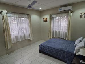 a bedroom with a blue bed and two windows at Daysha's place in Tokuse