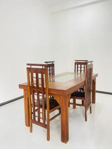 a wooden table with two chairs and a glass top at SH Villa in Weligama
